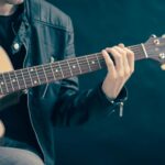 person holding brown and black guitar
